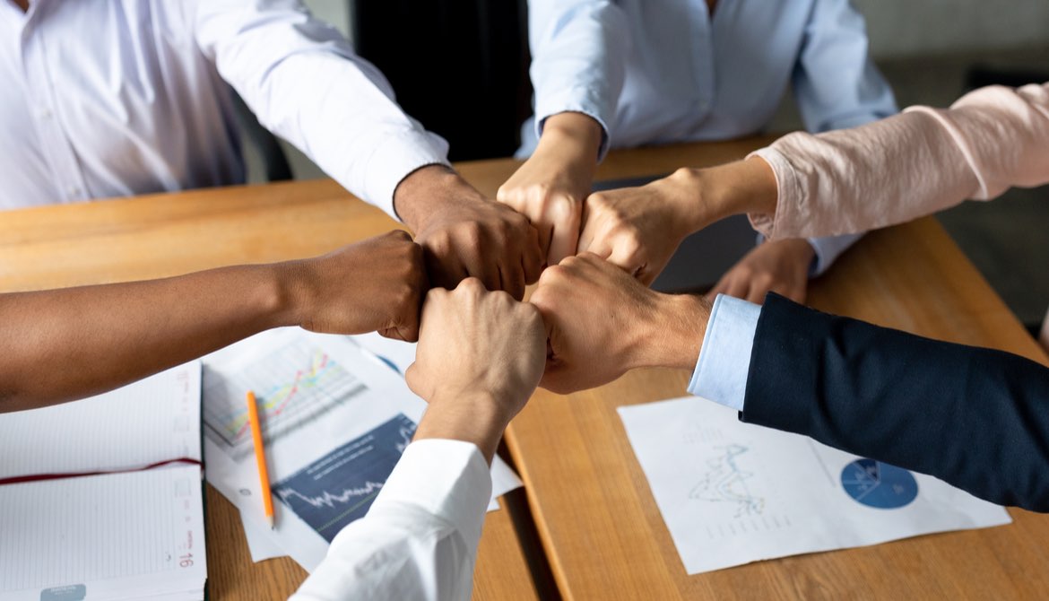 diverse fists together over a table with papers about finances