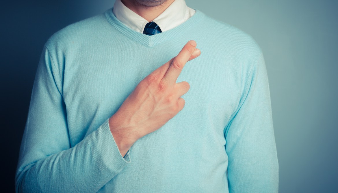 man with fingers crossed over his mint sweater