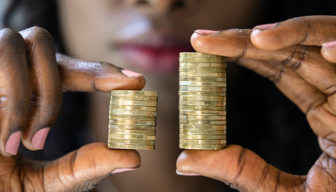Black woman holds two stacks of coins where one is noticeably smaller