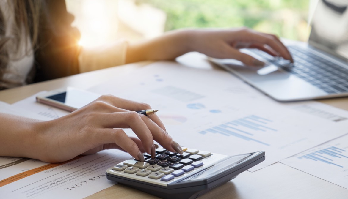 woman using calculator and laptop to do accounting