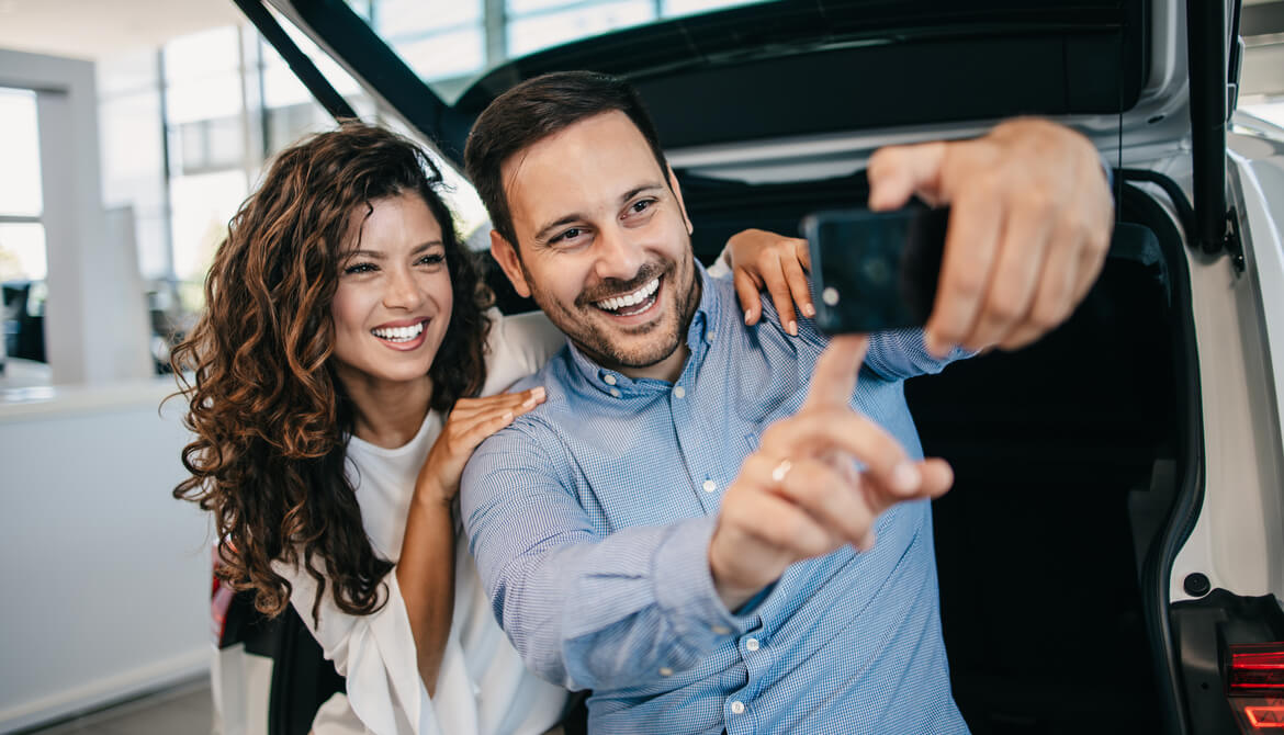 couple takes selfie when buying a card at a dealership