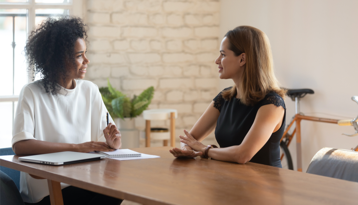 young female employee meeting with smiling Black female manager