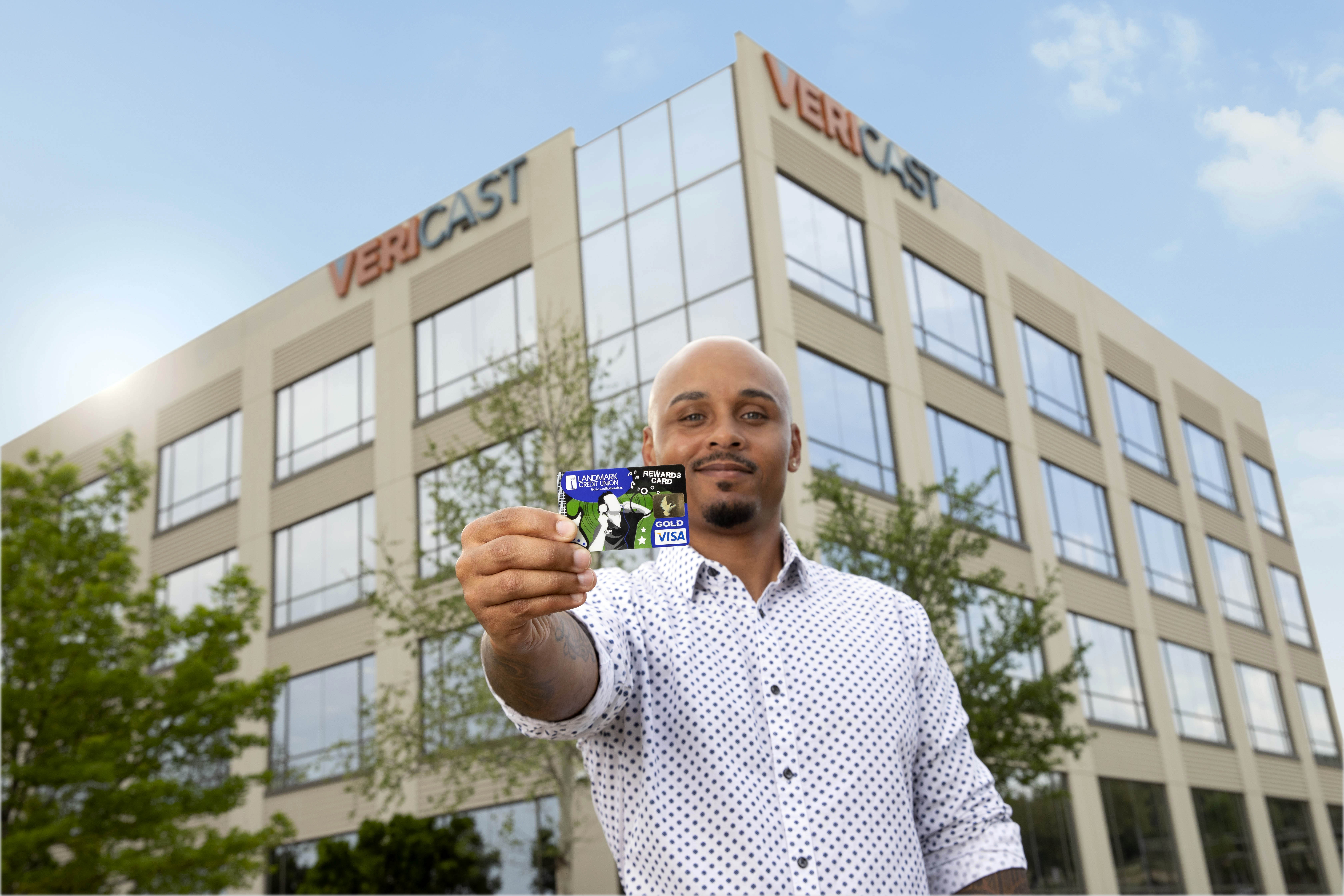 Josh Hatcher displays customized payments card in front of Vericast building