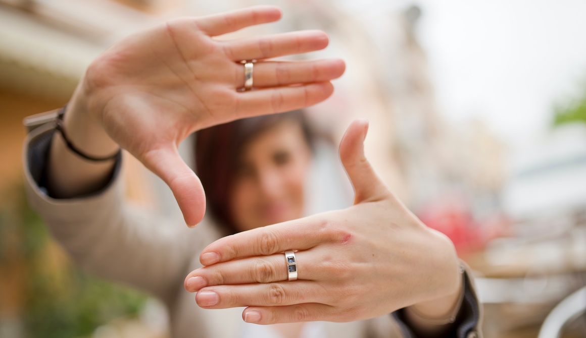 businesswoman out of focus in background holds out hands to form a square window in sharp focus in foreground