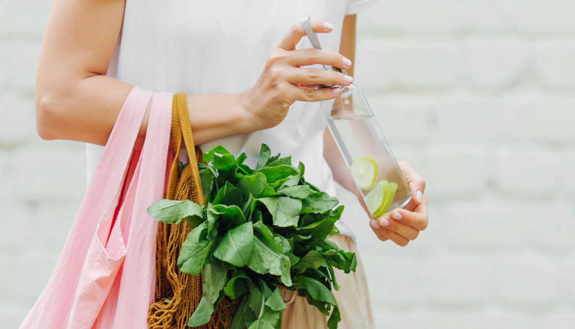 woman with greens in shopping bag and a water bottle