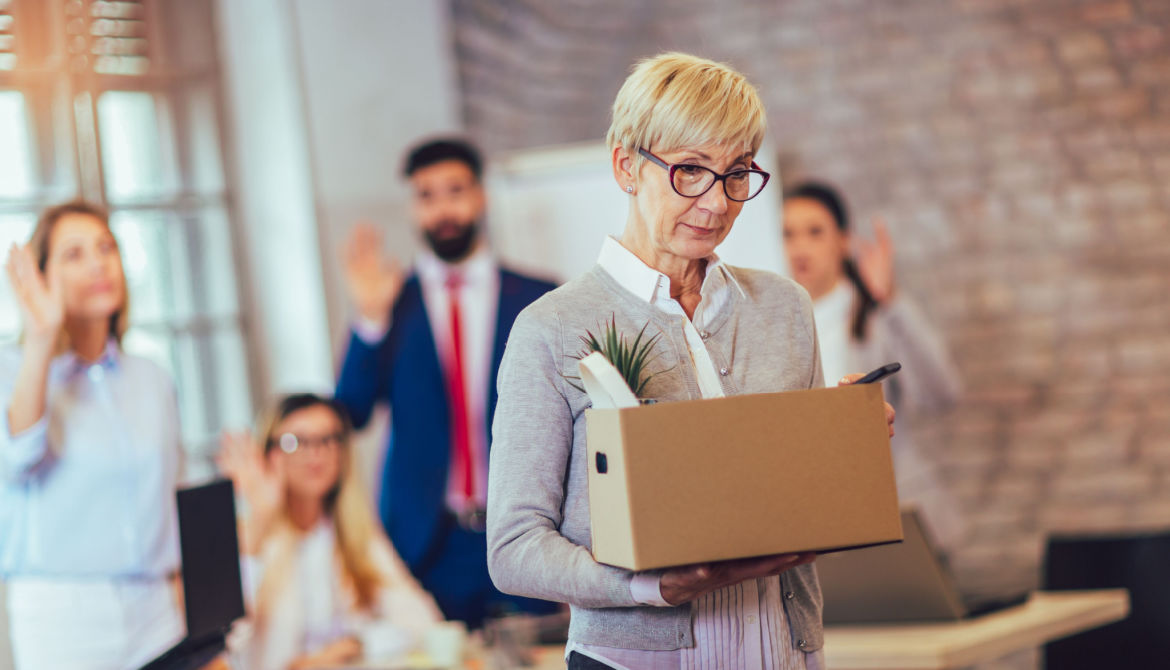 older person leaving workspace with box