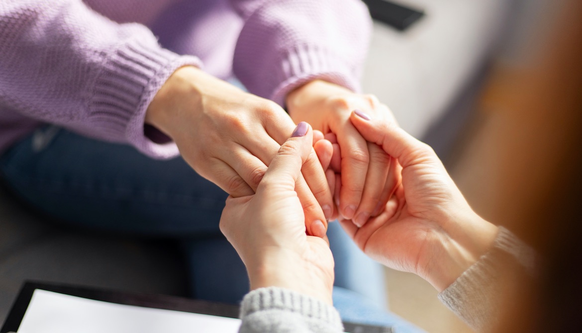 female colleague holding the hands of another employee to show care and support