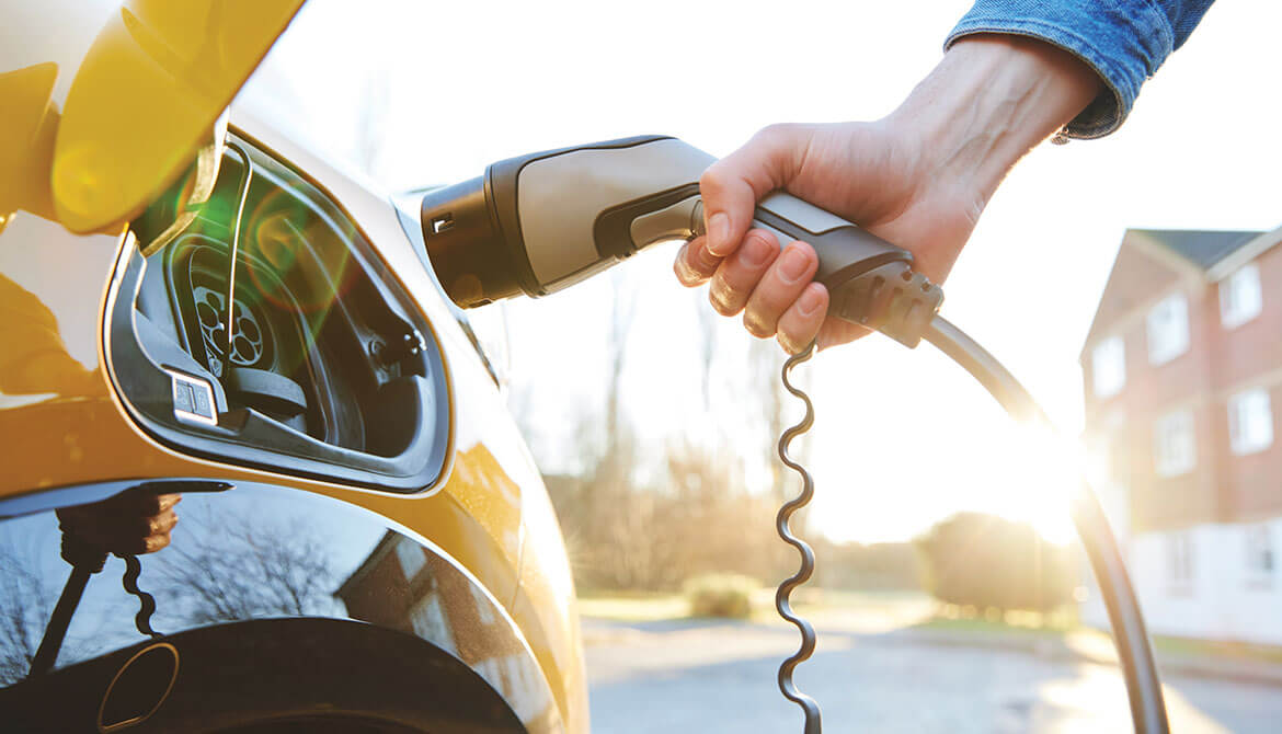 hand reaches out to plug in electric vehicle charger