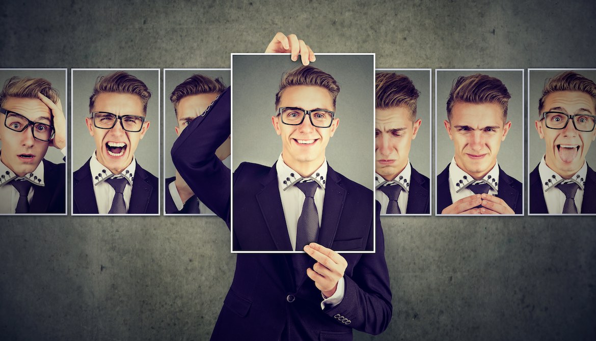 businessman choosing to hold up picture of positive personality from among other pictures expressing various emotions