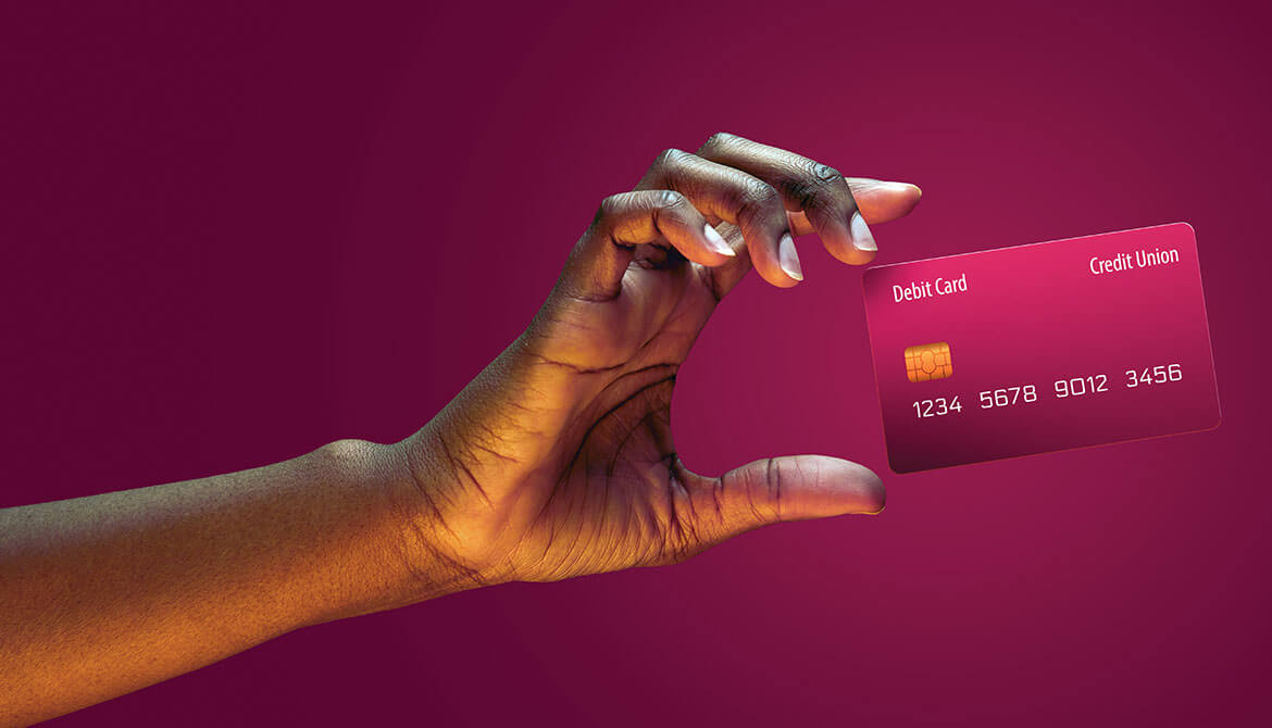 woman’s hand holding up a fuchsia debit card