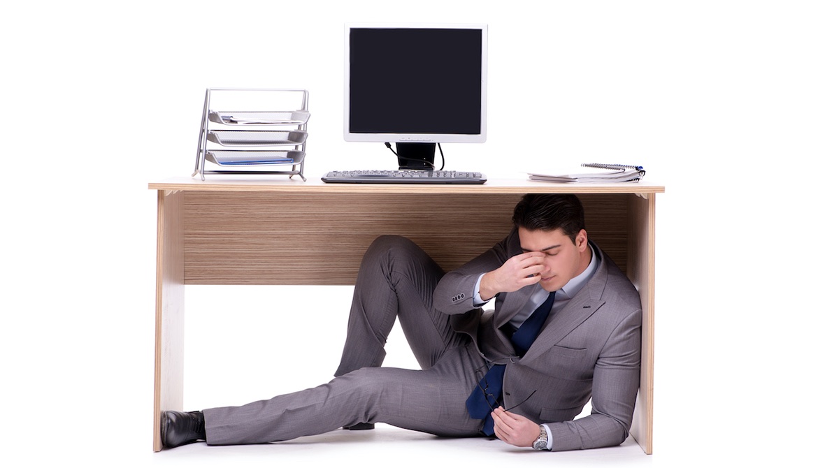 stressed tired business manager hiding under office desk