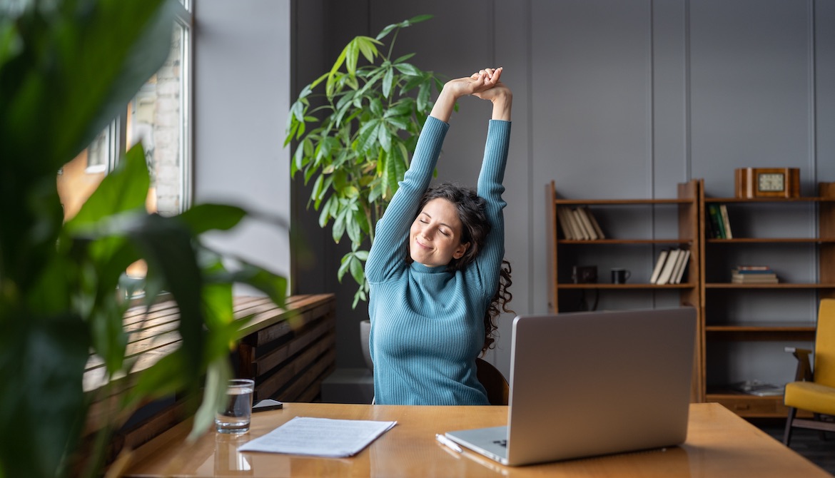 content employee stretching at her desk