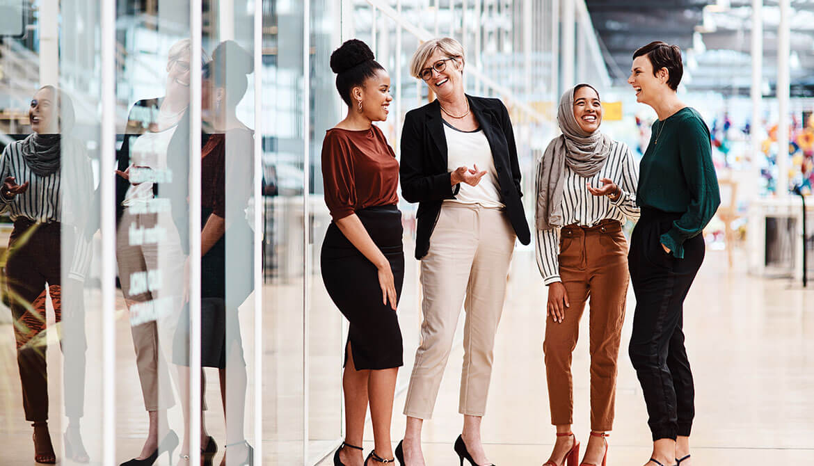 Group of businesswomen of diverse ages and ethnicities chat in the office 