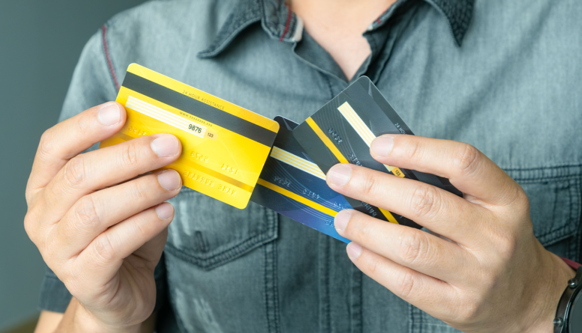 Man wearing green shirt is holding several credit cards to choose one 