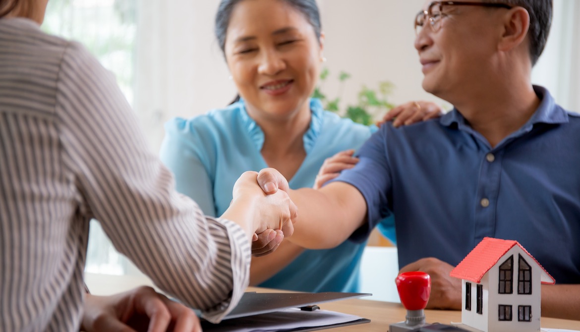 happy couple shakes hands with loan officer after securing a mortgage for new home