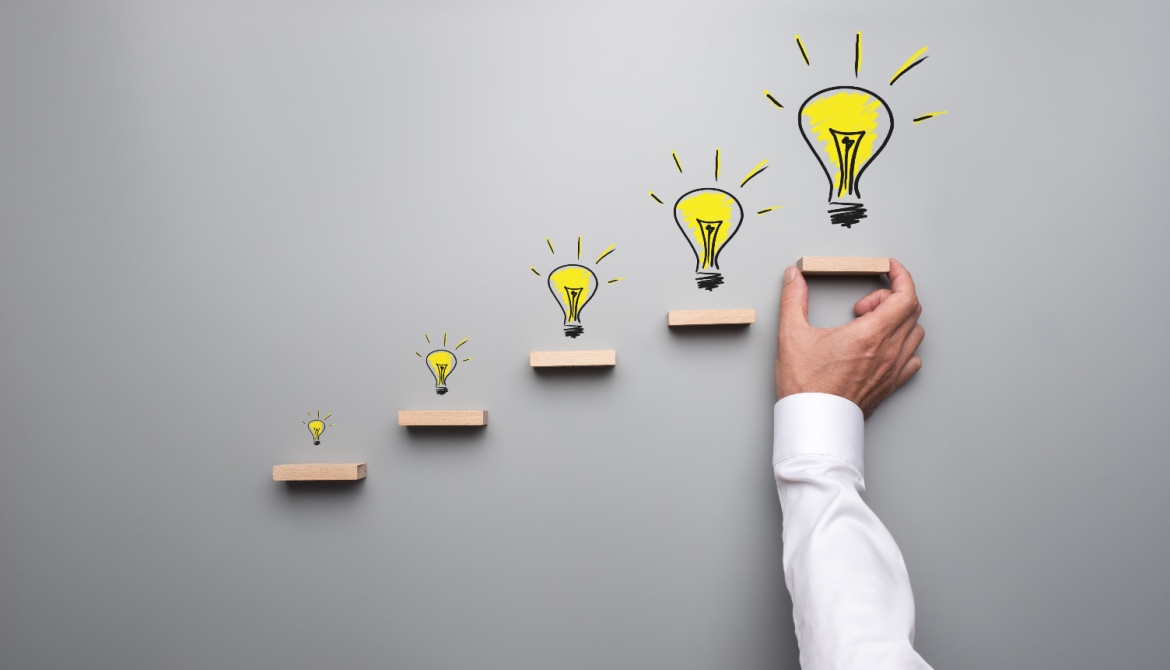 Five hand drawn light bulbs representing a financial services trends on wooden steps with male hand holding or placing the last step