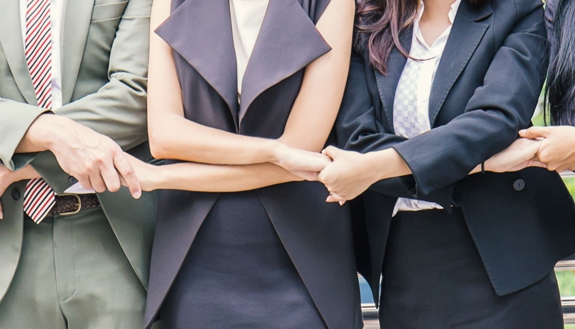 a row of business people crossing arms and holding hands
