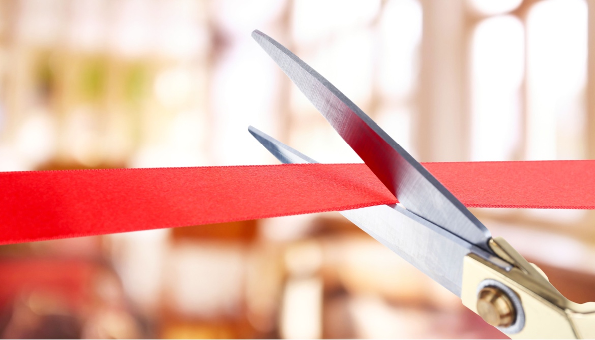 large scissors cutting a red ribbon