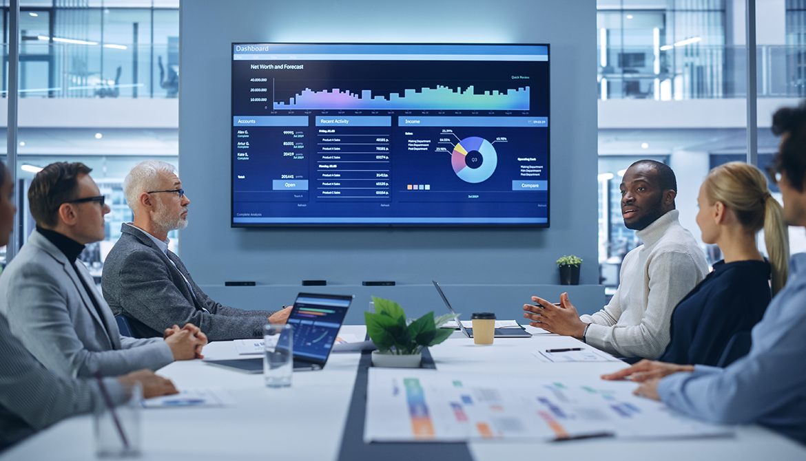 board members sitting and viewing large computer screen of graphs