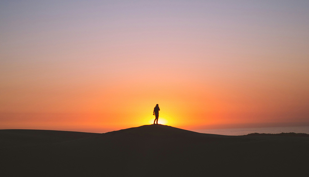 person silhouetted in front of a sunrise
