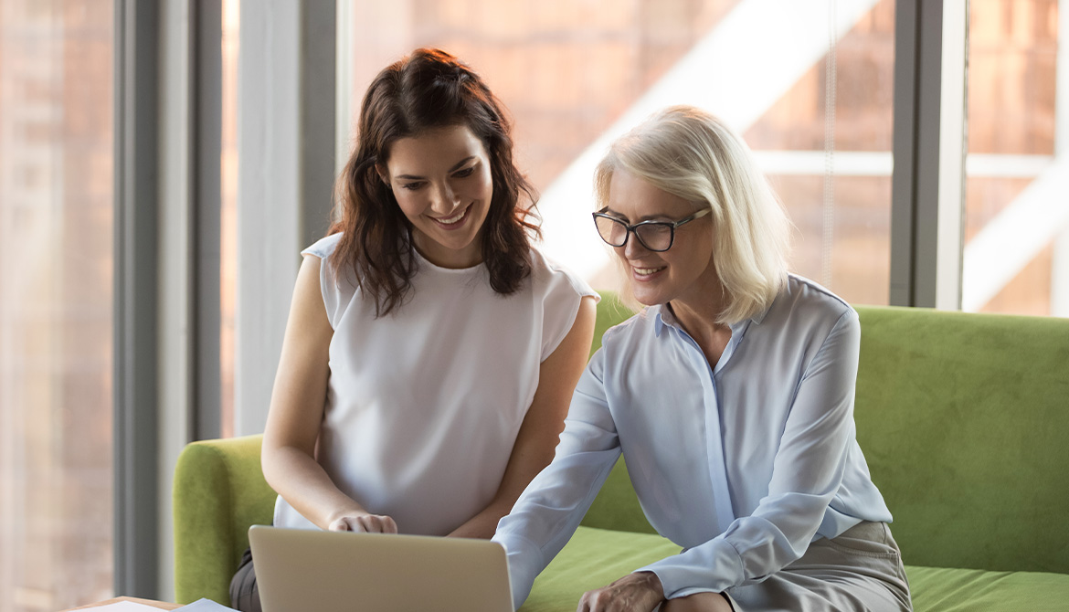 two women talking over a computer screen