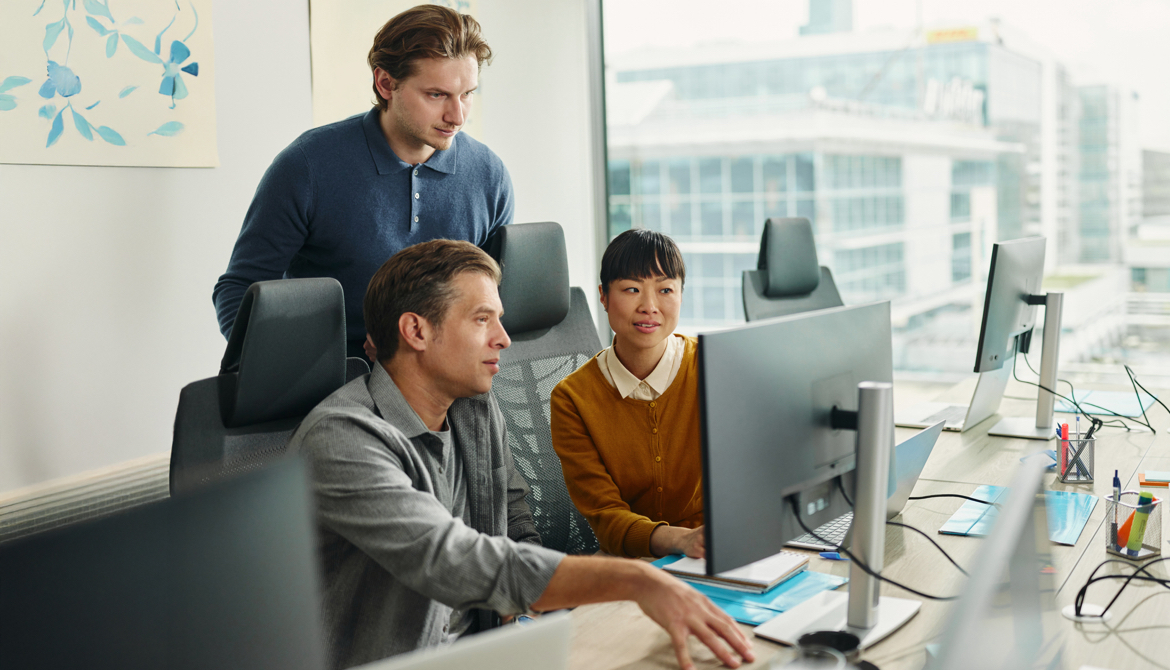 3 individuals looking at a desktop monitor