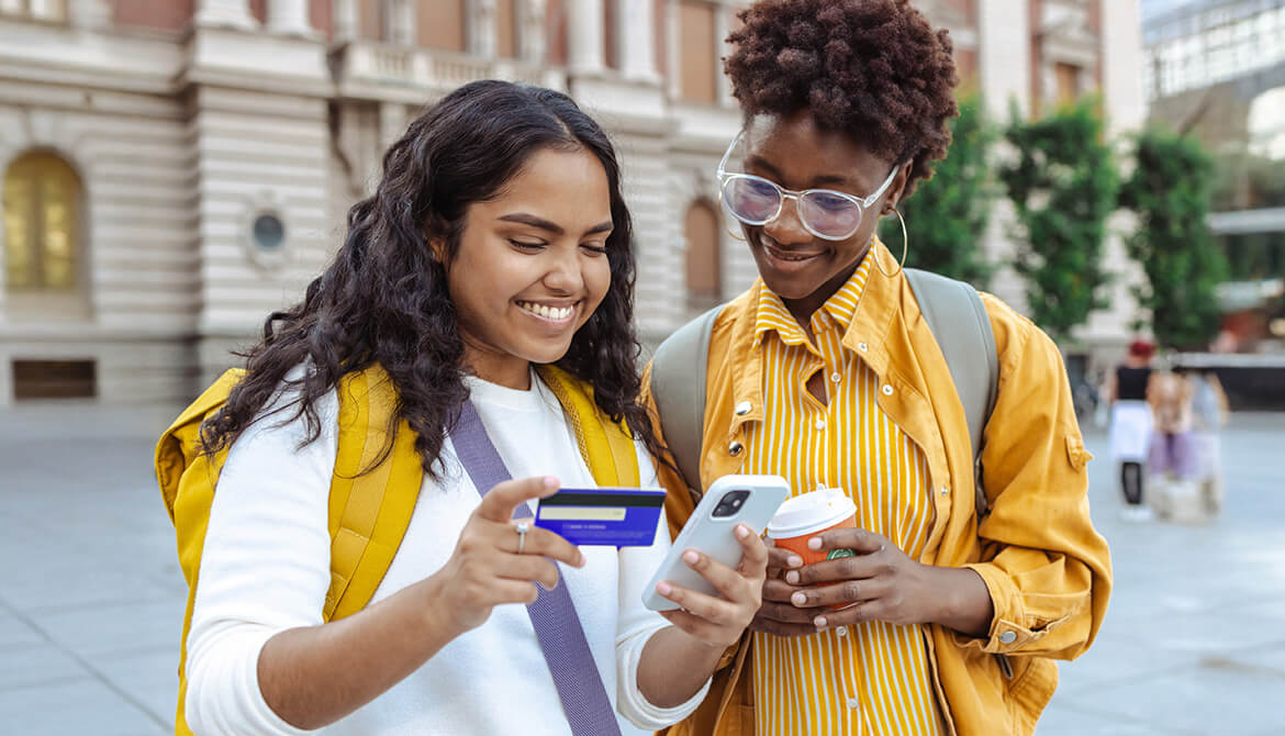 2 students looking at a smartphone and a credit card