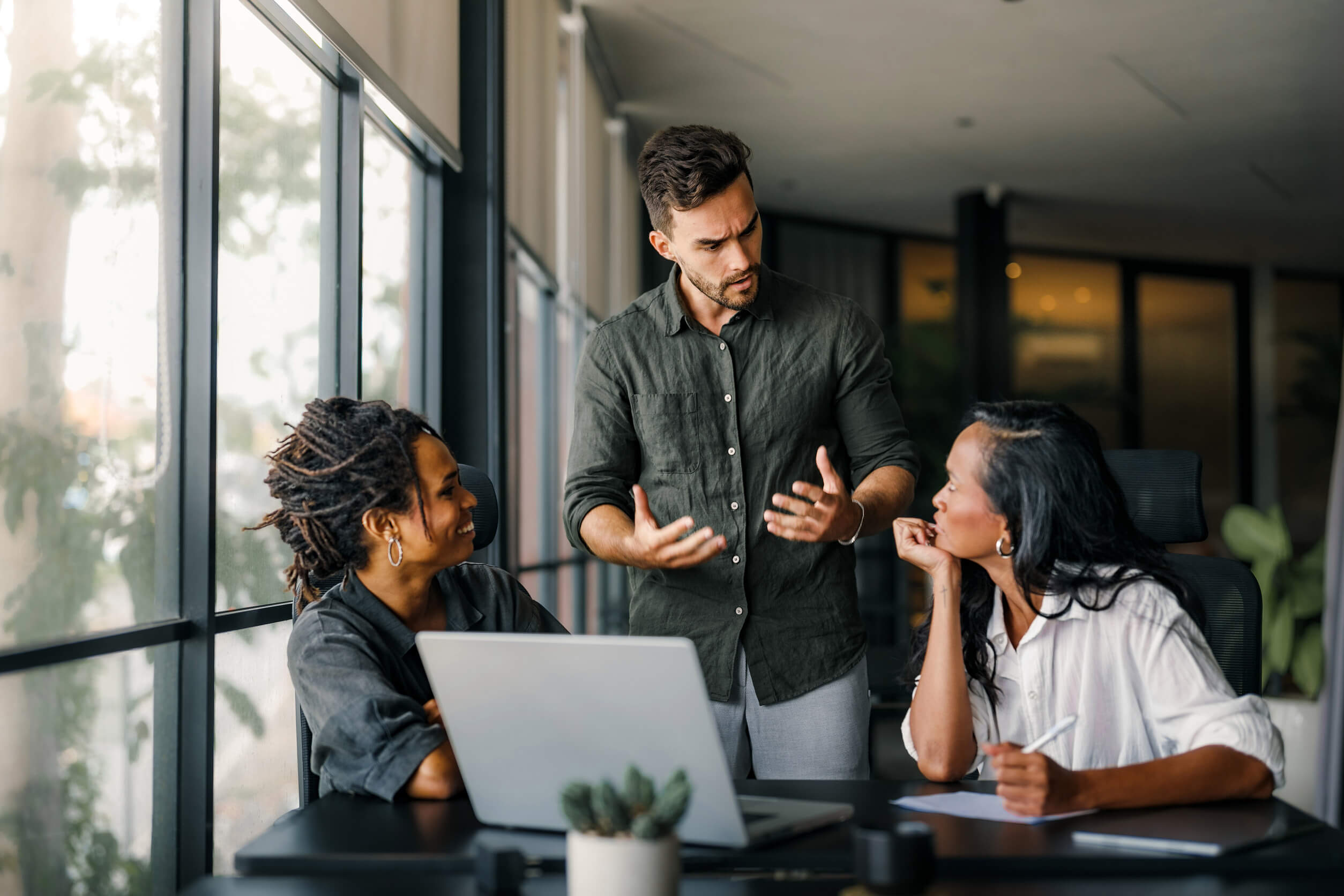 3 individuals talking behind a laptop