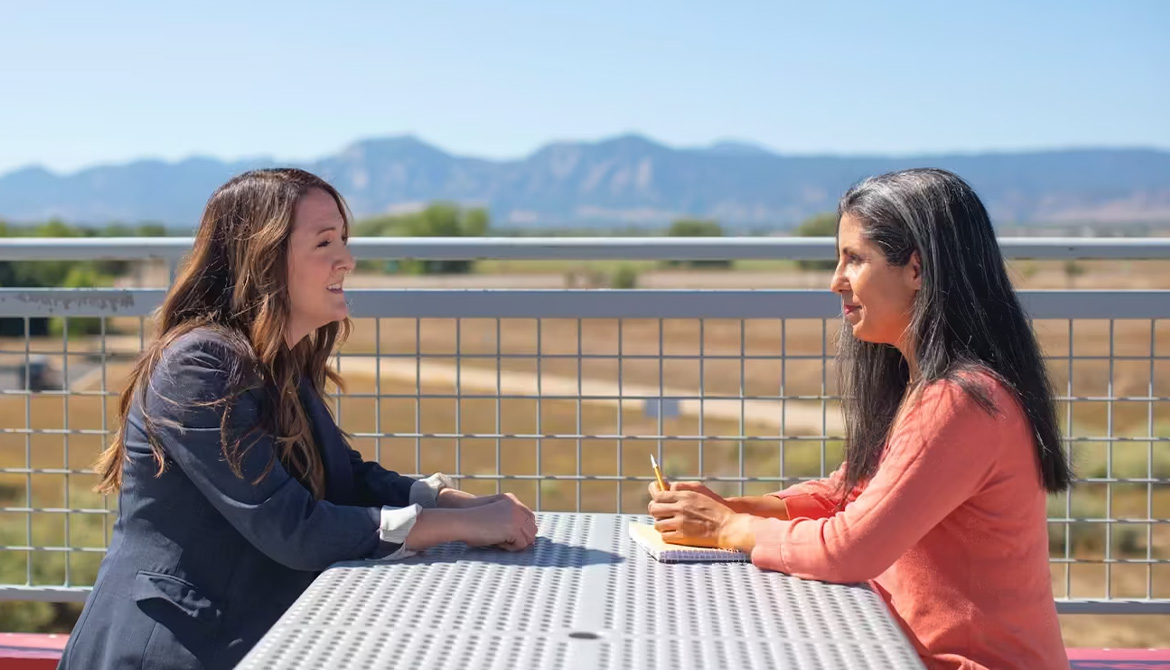 2 women talking at outdoor table