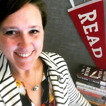 Kari Sweeney poses in front of a "read" banner