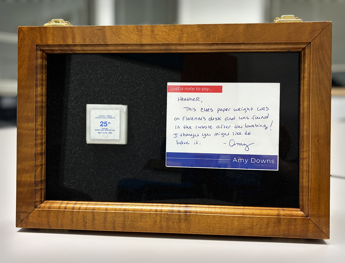 The CUES paperweight accompanied by a handwritten notecard.