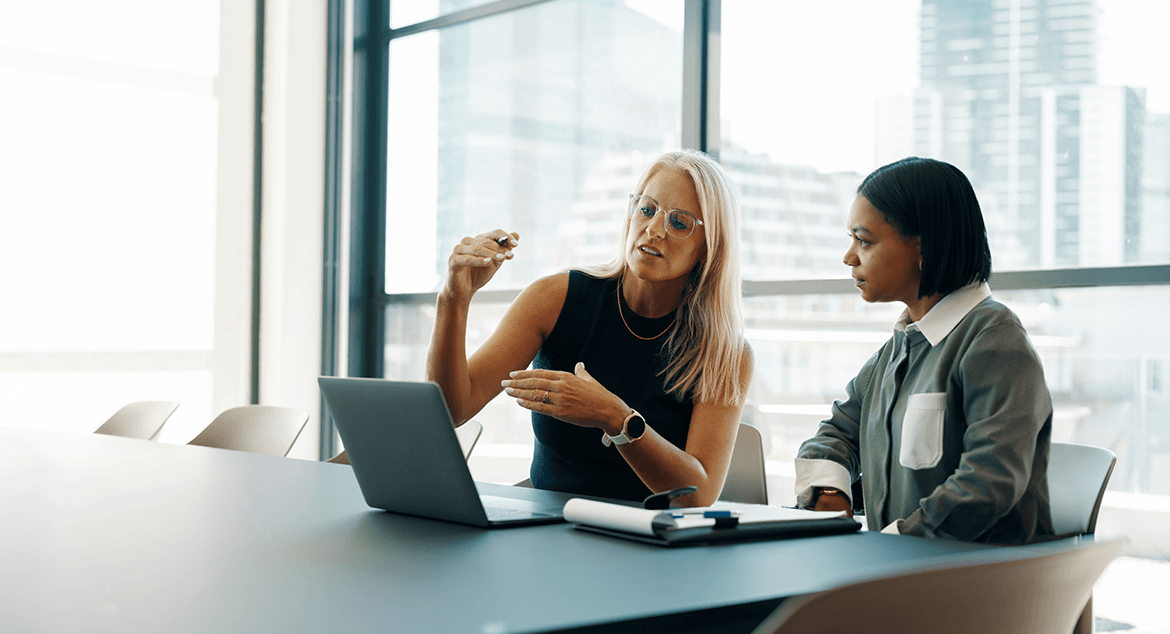 2 women looking at a laptop on a table