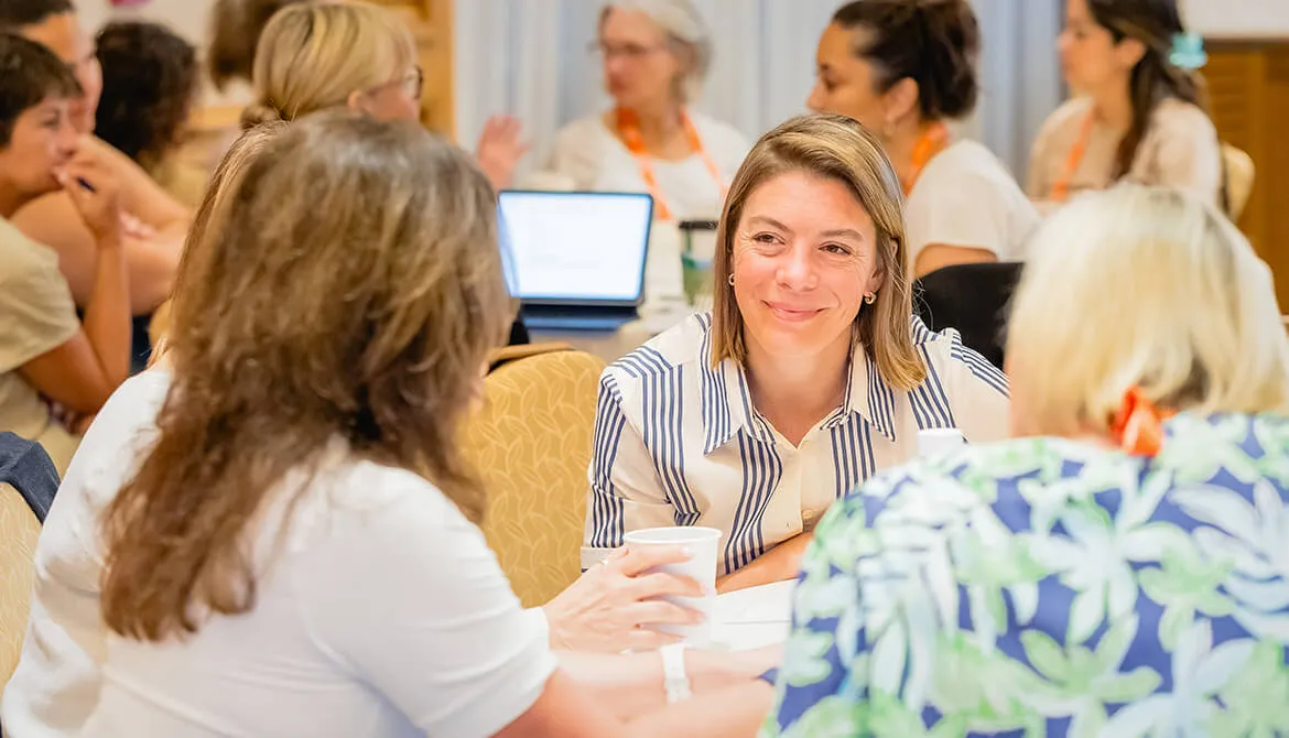 women engaging in conversation around a table at CUES Symposium conference