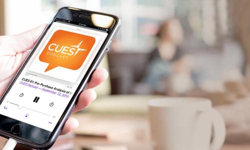 Hand holding mobile phone with CUES Podcasts in the display