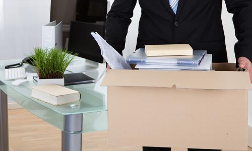 Fired employee carrying a box of his belongings away from the office