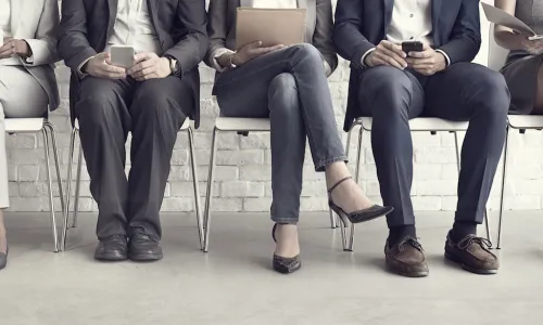 Five job candidates waiting on chairs without faces showing to know their age and race