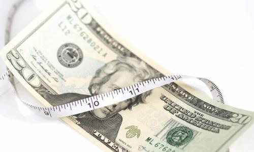 measuring tape squeezing a $100 bill