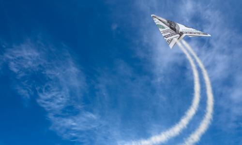 a paper airplane dollar flys through the sky