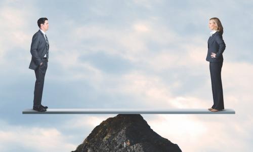 man and woman balance on top of a rock