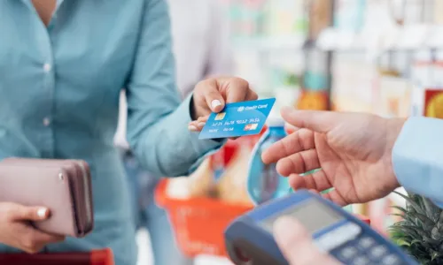 Woman at the supermarket checkout paying using a credit card