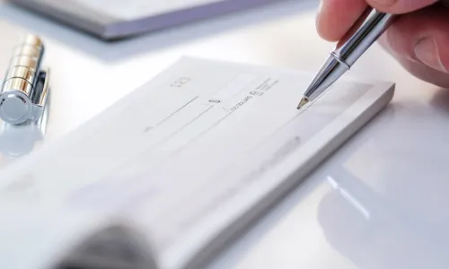 person writing a check with a silver pen