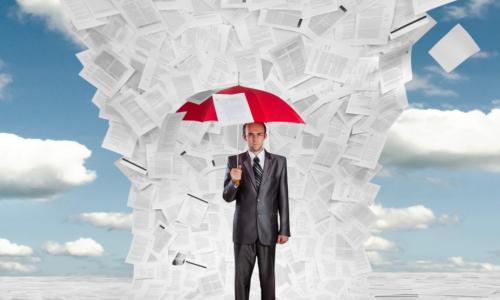 businessman holding umbrella under a deluge of documents