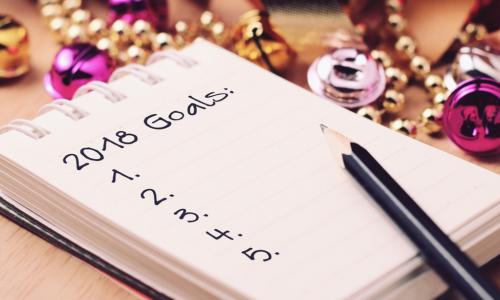 A pencil and notepad that lists 2018 goals