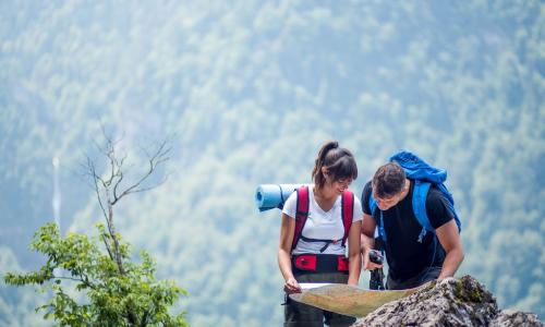 young male and female hikers using a map to navigate