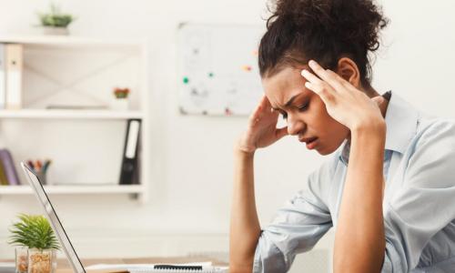 Tired African-American business woman with headache at office