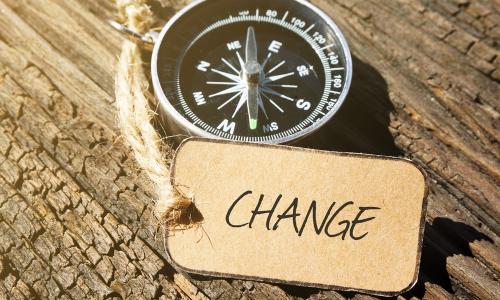 compass and paper tag labeled CHANGE sitting on old wood