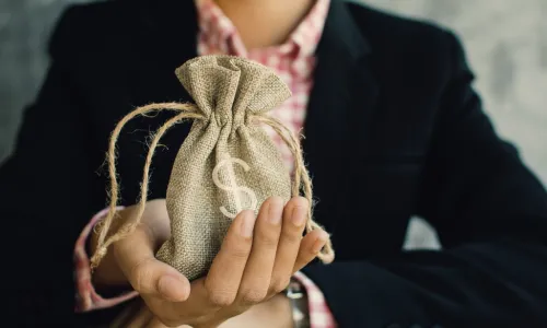 female executive with burlap bag with money symbol in her hand