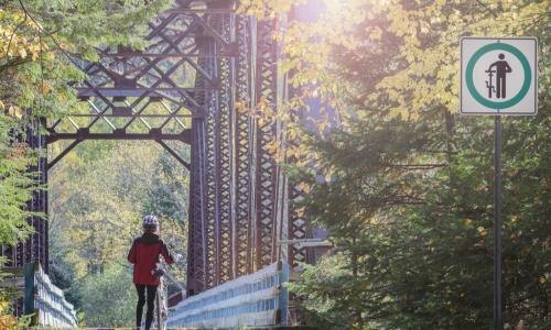 female bicyclist follows the rules by walking her bike across a bridge