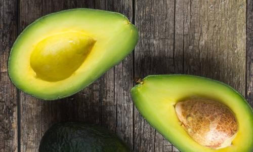 sliced avocados with pit intact on a wooden background