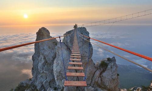 Precarious rope bridge leading to a mountain peak